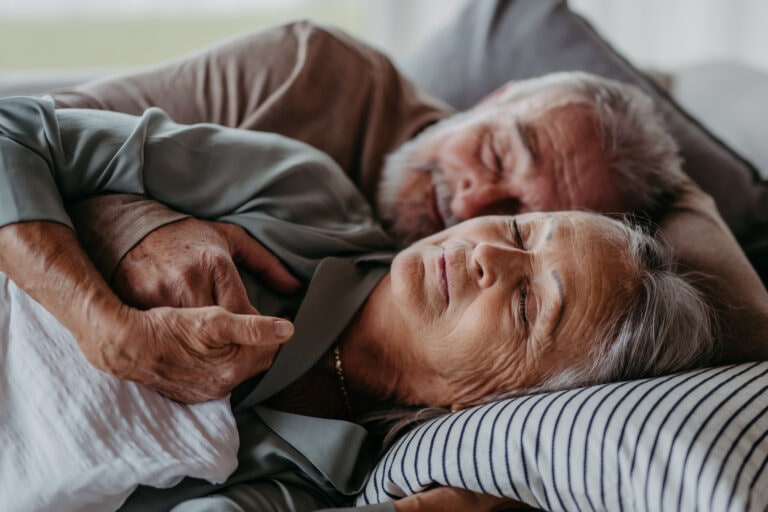Front view of senior couple lying in bed and sleeping.