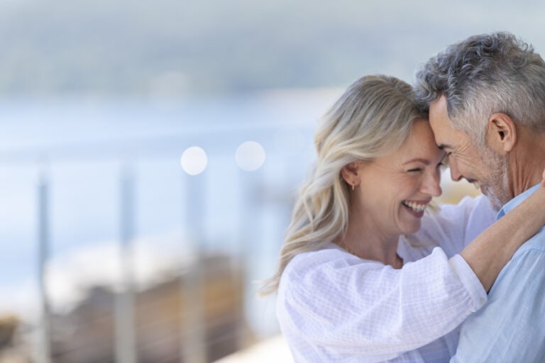 Mature couple dancing at a waterfront home or holiday villa.
