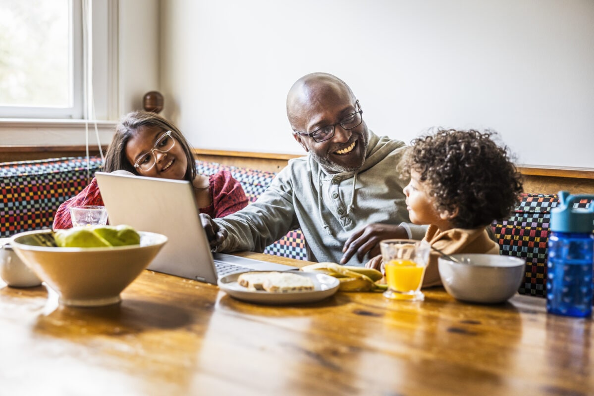 Father multitasking with children at breakfast