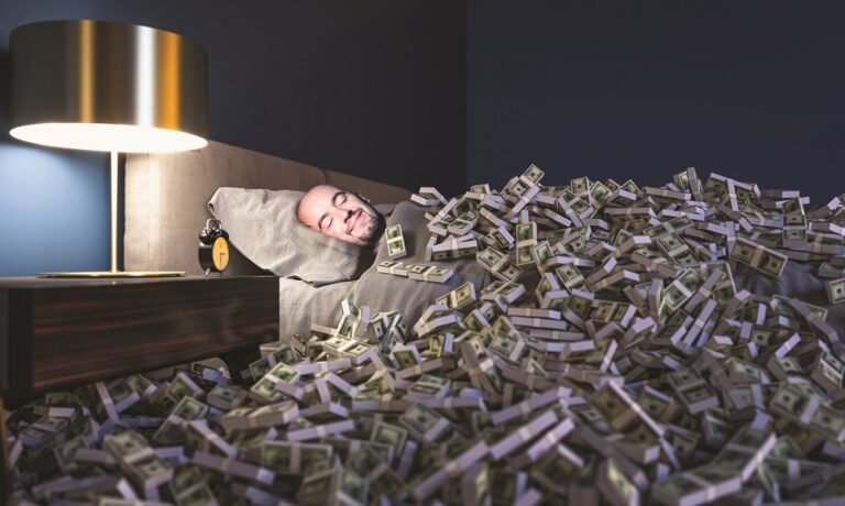 Smiling man sleeping in a bed covered with dollars