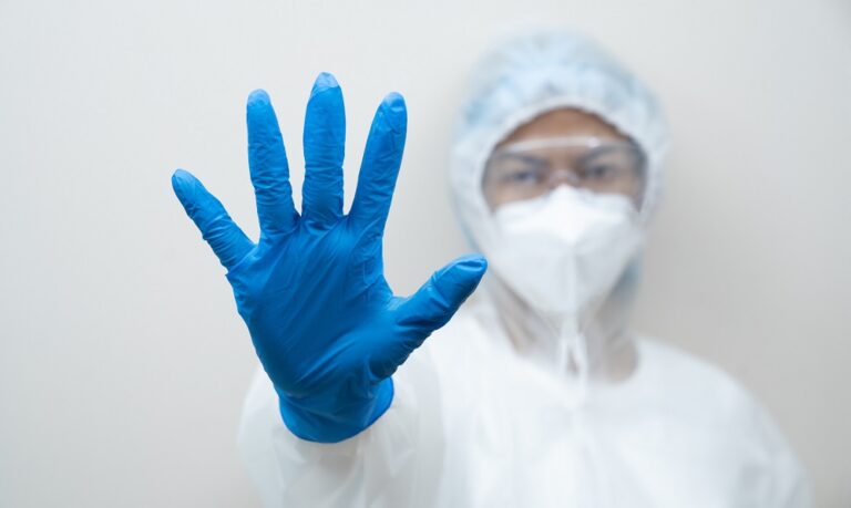 Doctor with full body suit and mask showing stop sign with his hand on white background. Coronavirus or covid-19 global epidemic. Stop COVID-19 coronavirus outbreak.