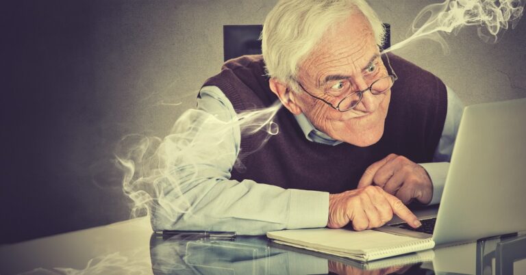 Stressed elderly old man using computer blowing steam from ears