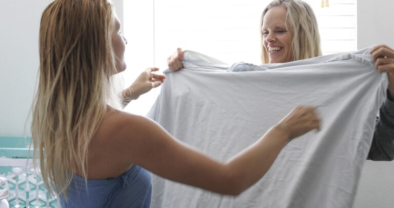 Mother and daughter fold laundry in the morning