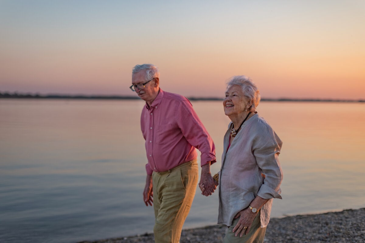 A senior couple enjoying summer vacation by the sea, celebrating their wedding anniversary.