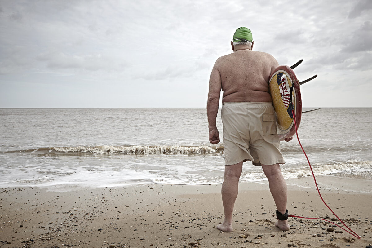 Elderly overweight surfer with back to camera