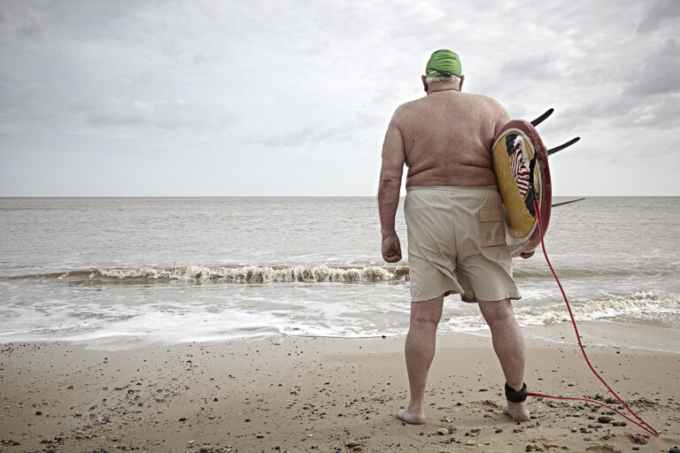 Elderly overweight surfer with back to camera