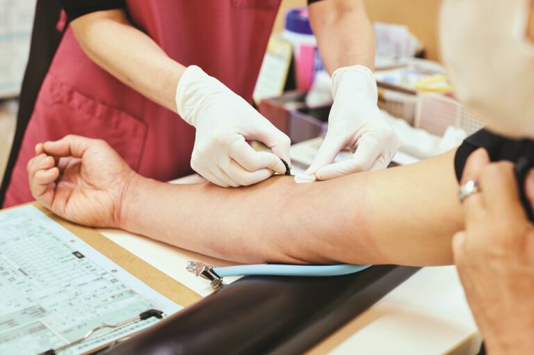 Female nurse collects blood from senior patient for testing at hospital