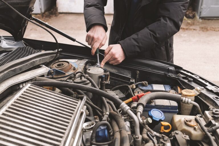 Man fixing his car engine under the open hood