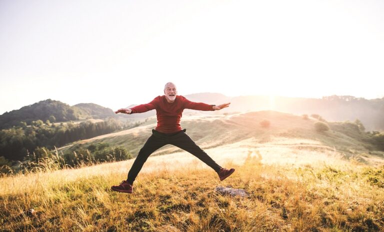 Senior man jumping outdoors in nature in the foggy morning. Copy space.
