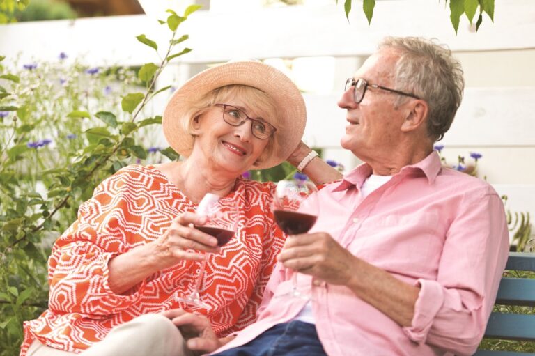 Senior couple talking to each other while having wine in garden