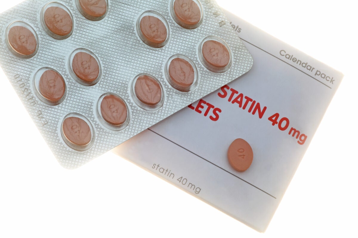 Statin pills in blister pack with box on white.