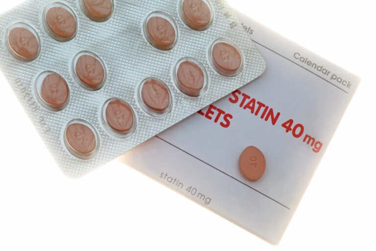 Statin pills in blister pack with box on white.