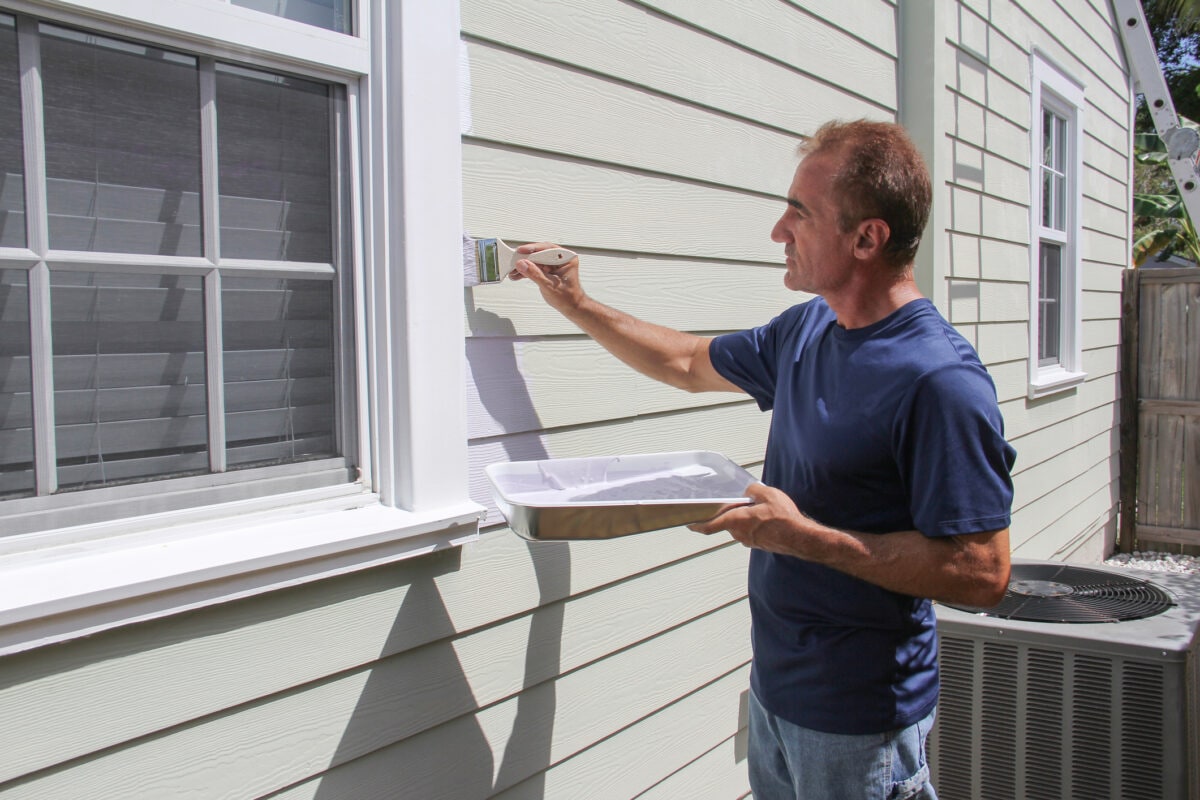 A man outdoor painting his home.