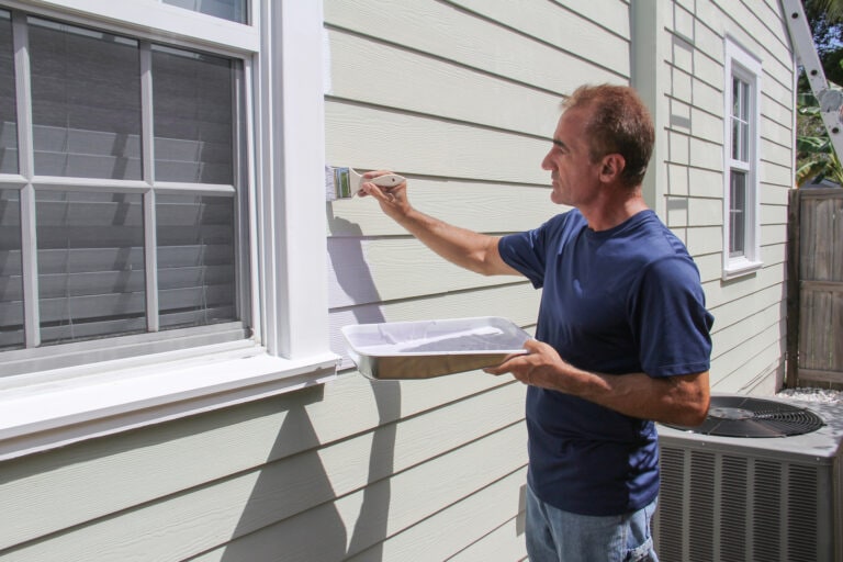 A man outdoor painting his home.