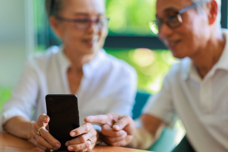 Senior couple enjoying with smartphone on the table in living room.