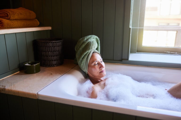 Mature woman soaking in a bubble bath with her eyes closed