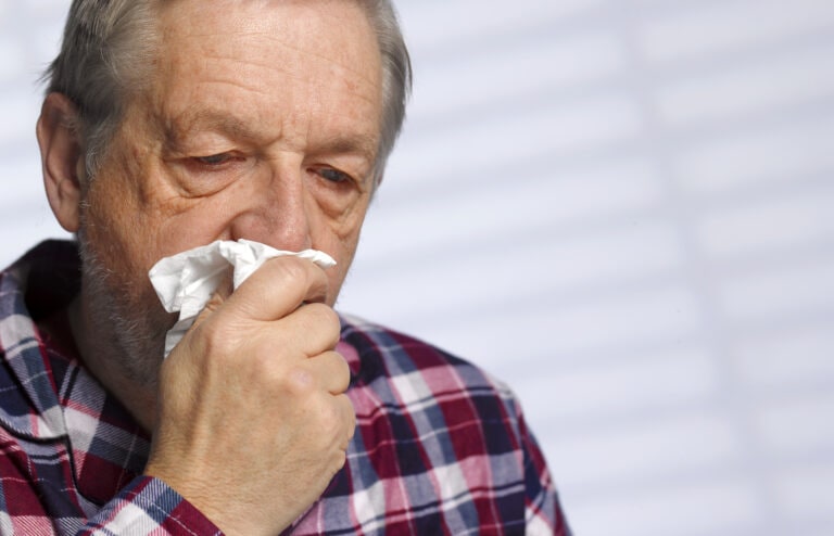 Man coughing into a tissue