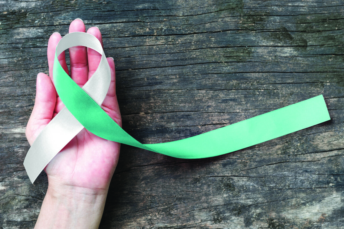 Teal and white ribbon for Cervical Cancer awareness campaign concept on woman helping hand support on old aged wood