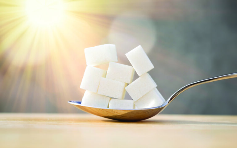 Spoon with nine lumps of sugar equivalent to the content in sugar of a refreshing drink illuminated by sunlight.