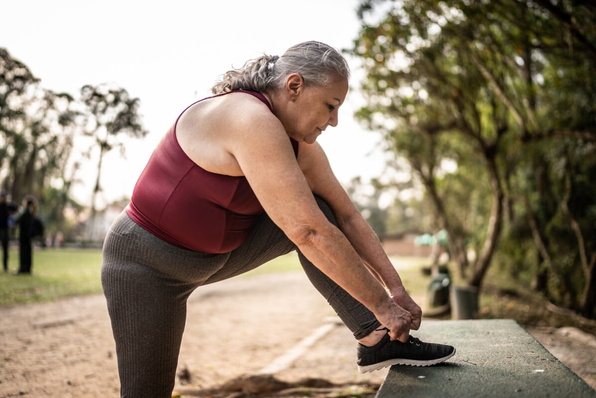 Senior woman tying shoelace in a park