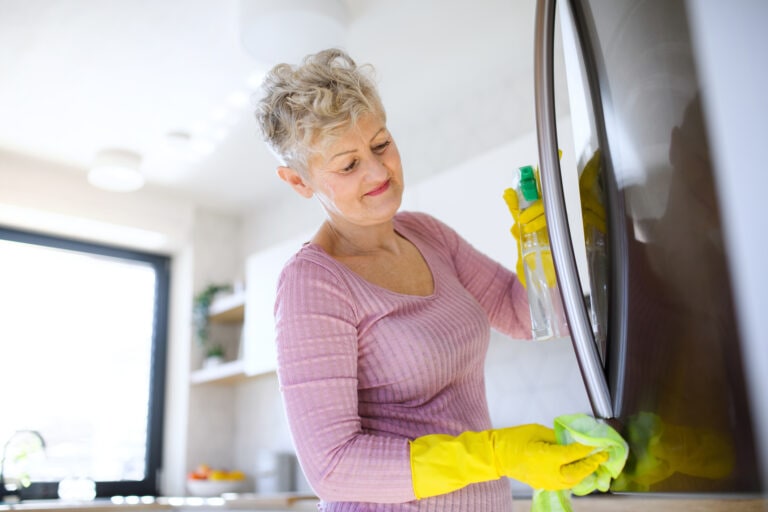 Senior woman indoors at home, cleaning kitchen.