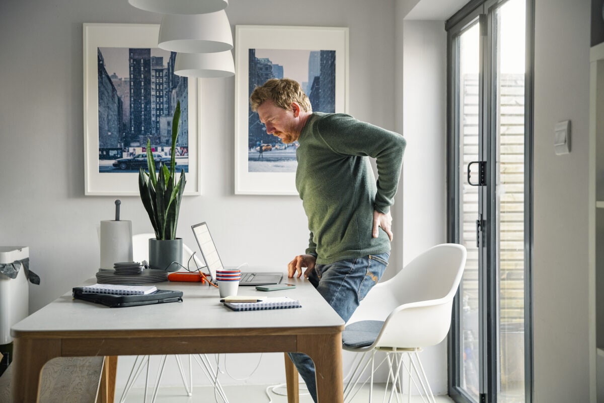 Mature man working from home. He suffers from back pain