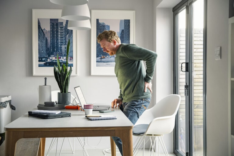 Mature man working from home. He suffers from back pain