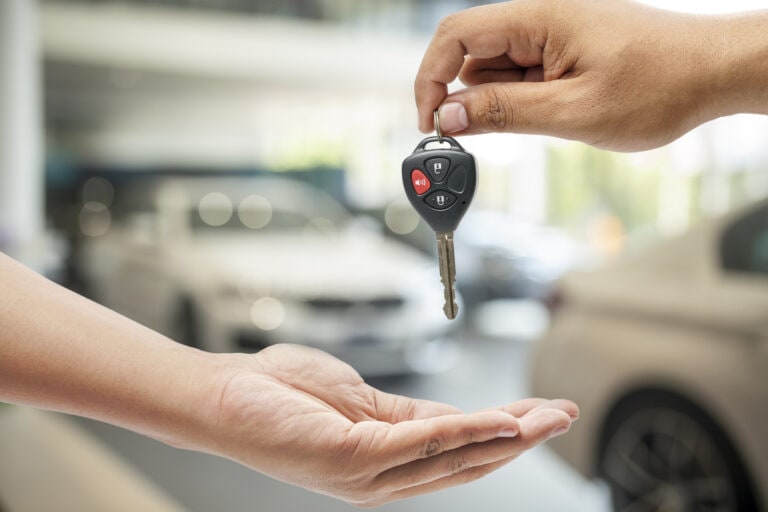 Car dealership.Young man receiving car key from saleswoman