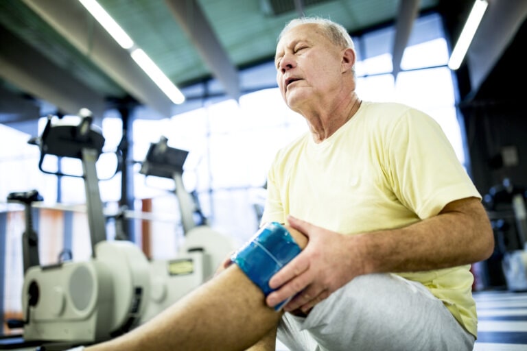 Senior man holding ice pack on knee