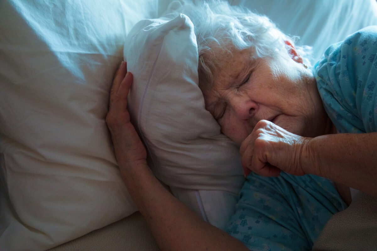 Sick Elderly Woman in bed coughing