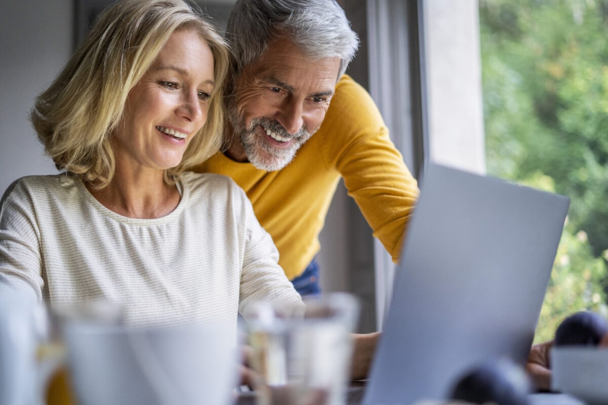 Smiling mature couple using laptop at home