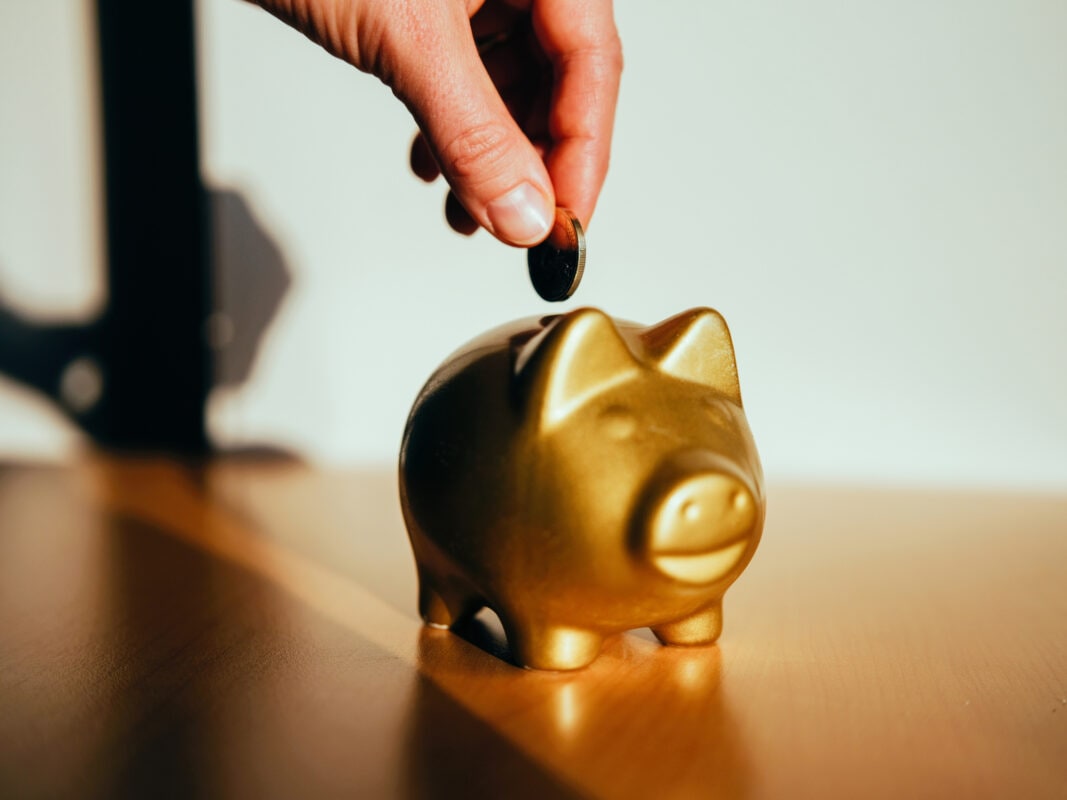 Putting a coin in a golden piggy bank.