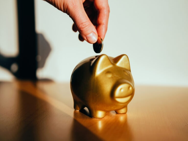 Putting a coin in a golden piggy bank.