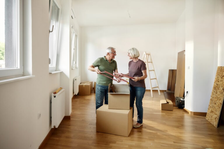 Happy mature couple unpacking their belongings after moving into a new home.