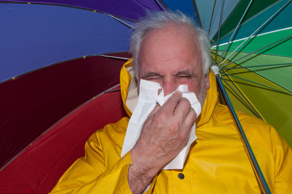 Unwavering in the rain, older gentleman struggles with a sniffles
