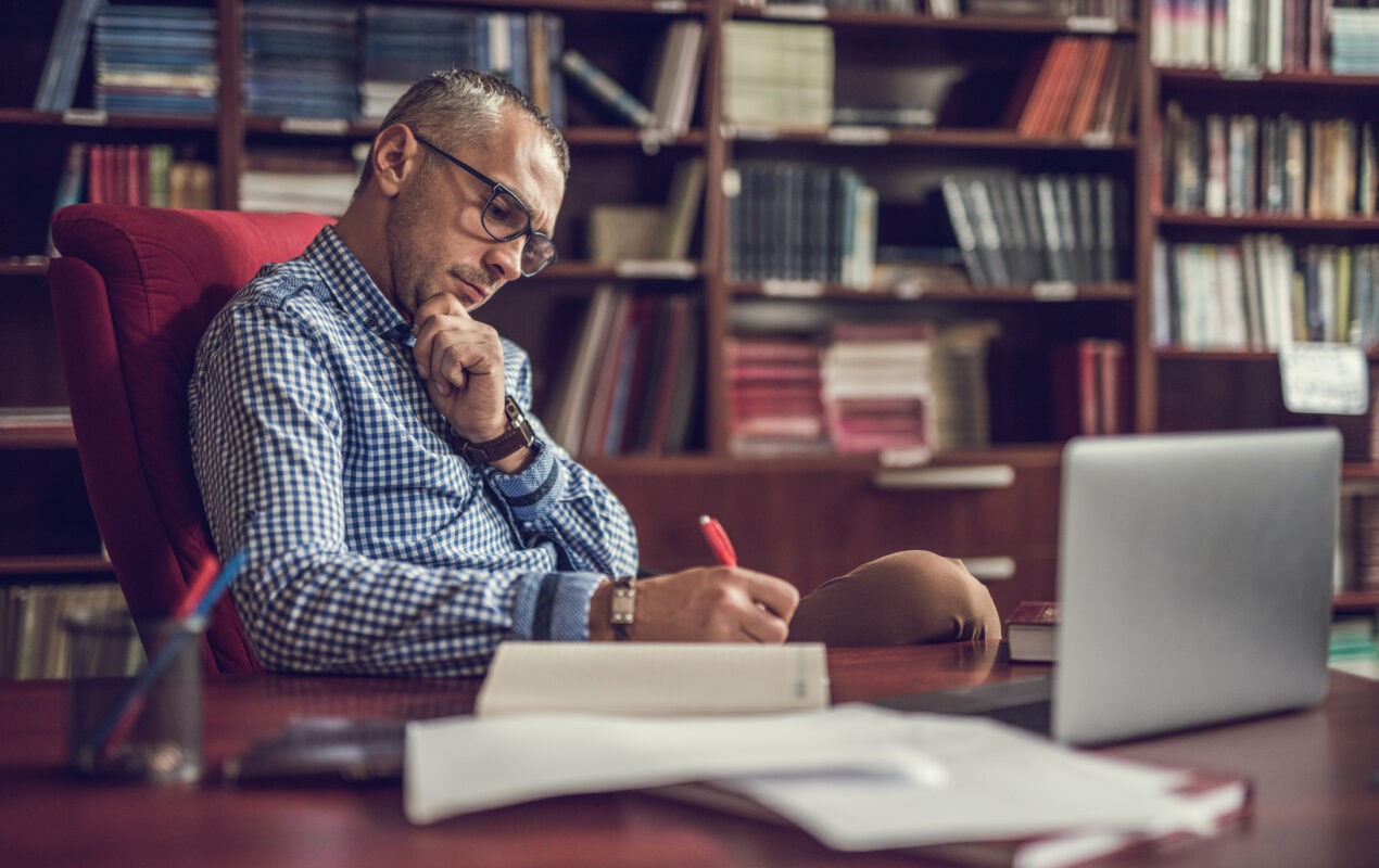 Male manager taking notes in home office.