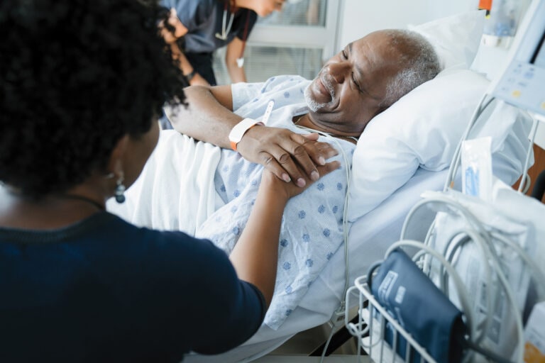 Father touching daughters hand while female doctor working in background