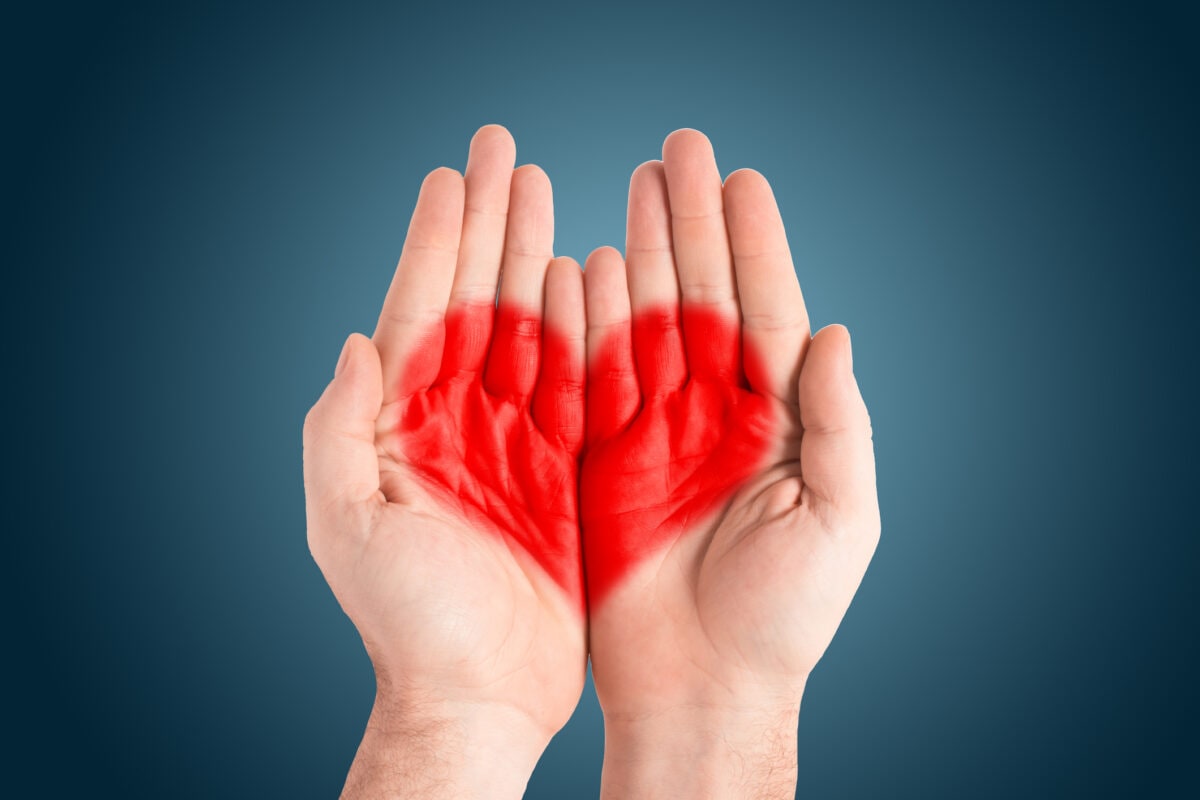 Red heart in the palms of a man