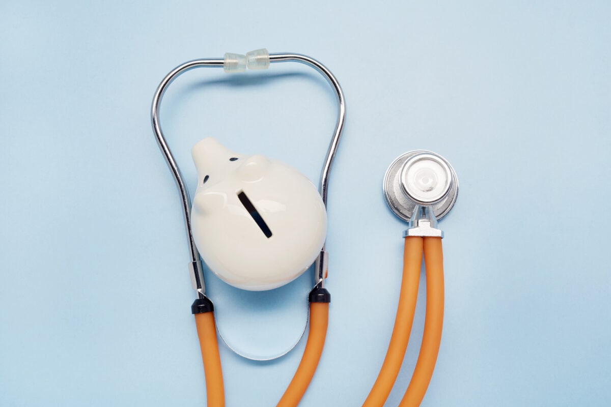 High angle view of stethoscope and piggy bank on blue background