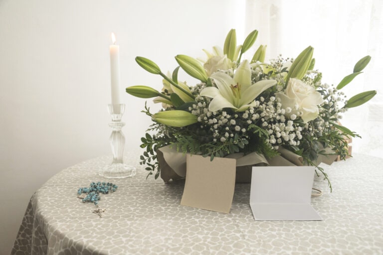 Illuminated candle with rosary and bouquet of flowers. Condolence card, farewell, mourning.