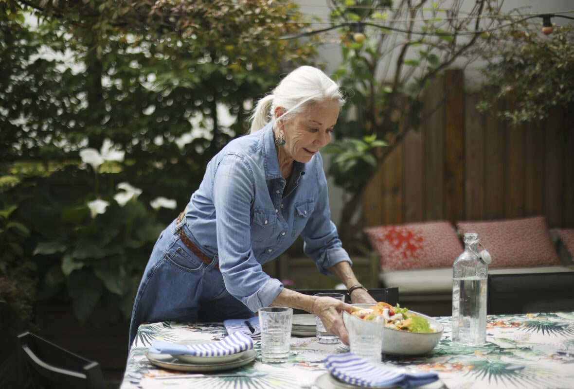 An elderly woman setting the table on her terrace