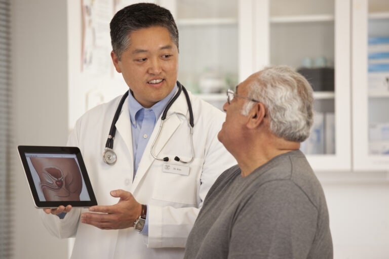 Doctor using digital tablet to talk to senior man