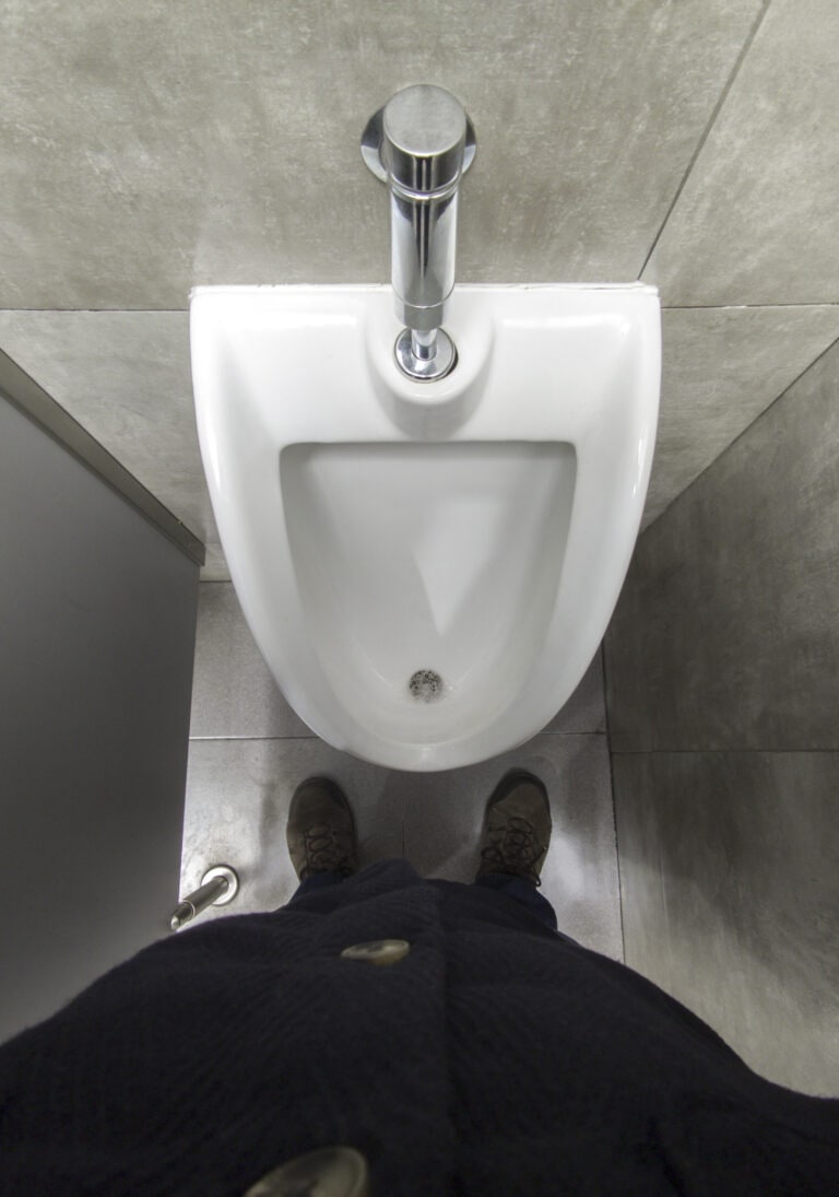 Mature man in front of a urinal. Overhead view
