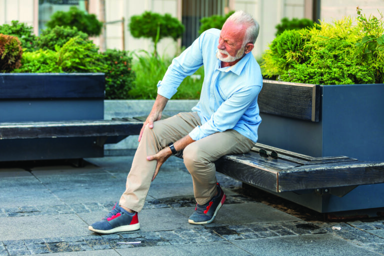 Senior Businessman with Knee Problems in the City Streets
