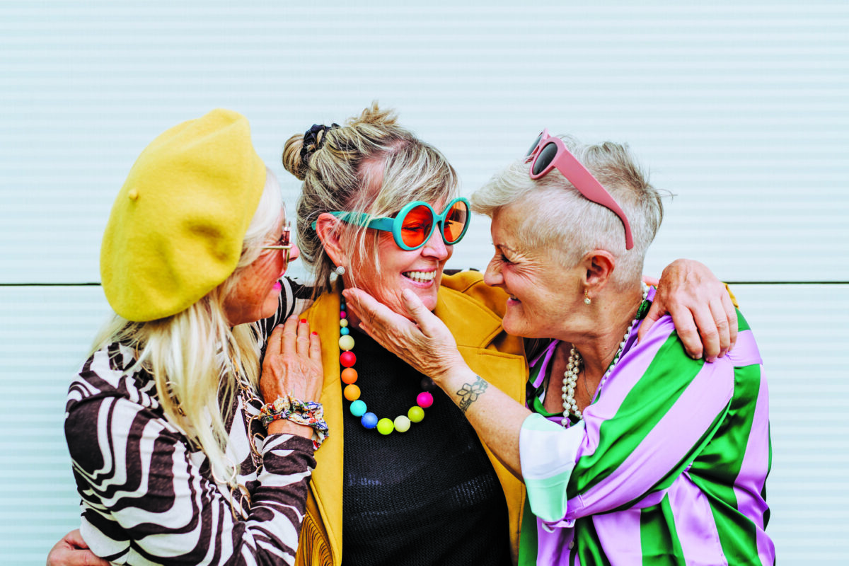 Portrait of happy three senior friends in colourful clothes.