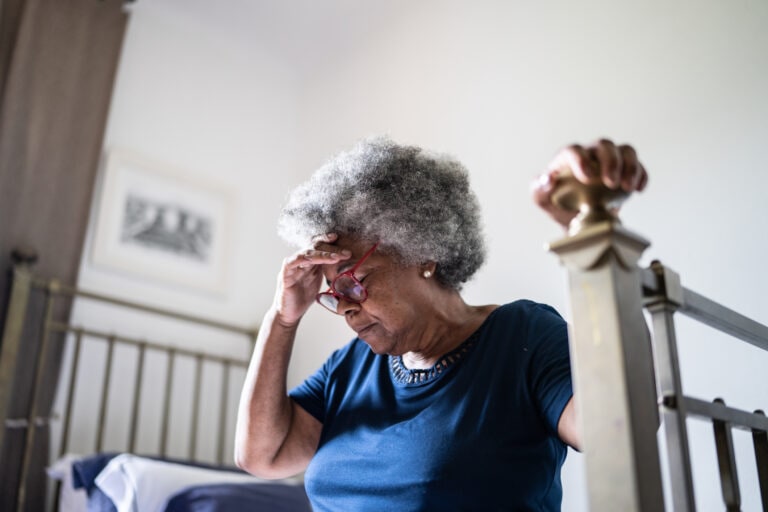 Senior woman with headache sitting in the bed at home