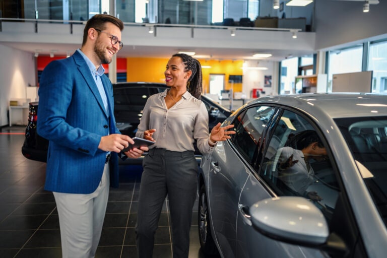 Salesman helping the male customer to choose a new car