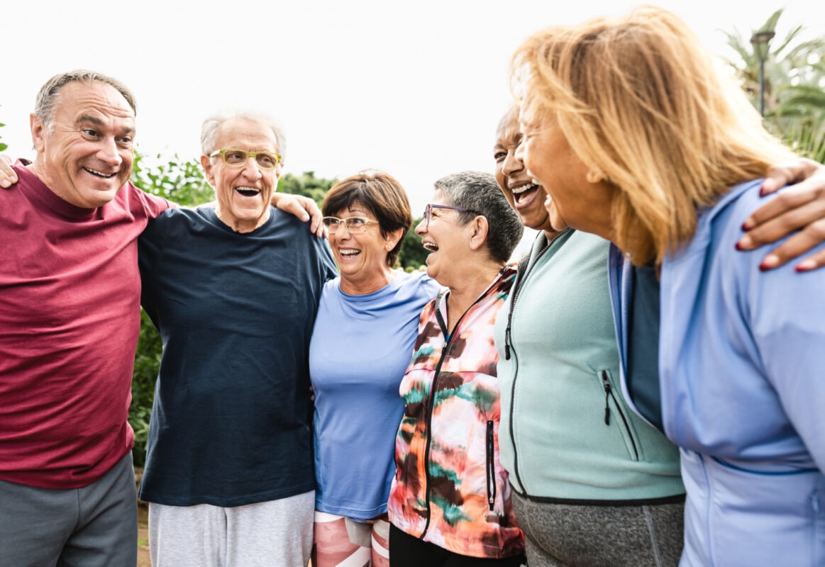Group of older people stand in a circle laughing