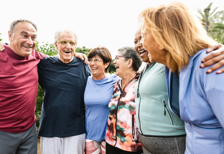 Group of older people stand in a circle laughing