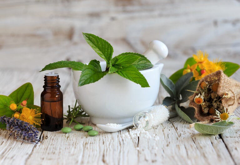Fresh herbs and essential oil bottle on a wood table